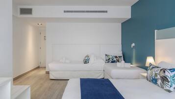 Une chambre d’hôtel moderne avec deux lits, une couverture bleue et une décoration aux tons blancs.