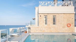 A pool area with a stone wall, a lifebuoy, and a view of the sea. - Hotel Planamar by Escampa Hotels (Castell-Platja d'Aro)