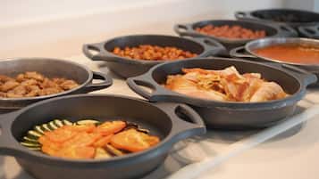 Un buffet proposant divers plats servis dans des poêlons en fonte, notamment des viandes et des légumes.