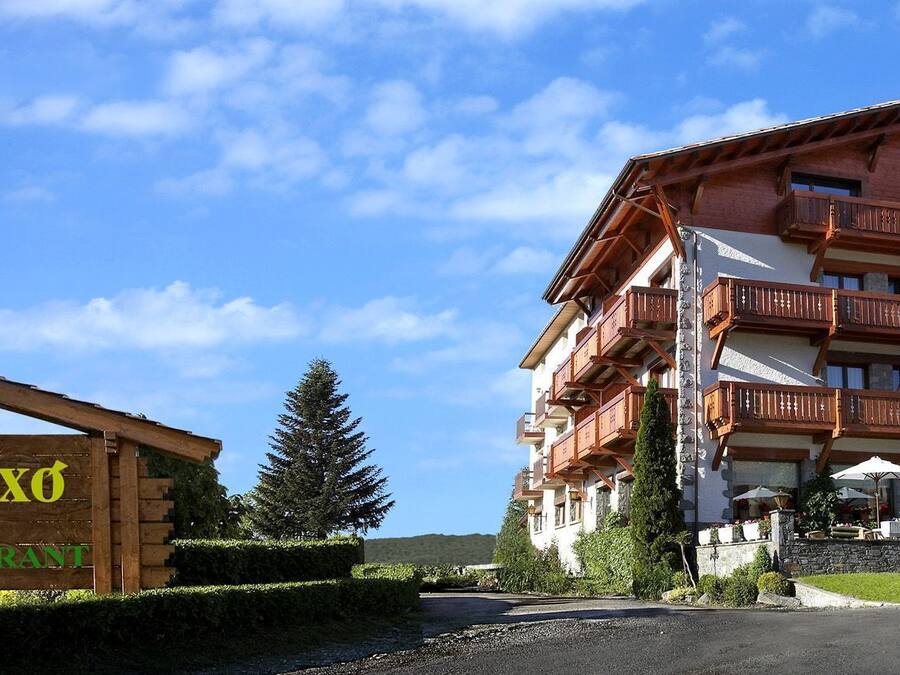 A hotel with a wooden signboard and a multi-story building with balconies.