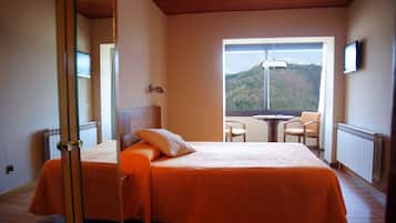 Un dormitorio con cama, ventana con vista a la montaña, mesa y dos sillas.