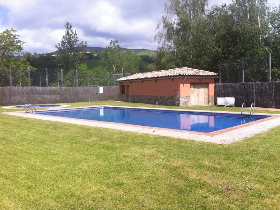 Une piscine rectangulaire dotée d’une plage carrelée, entourée d’une pelouse bien entretenue.