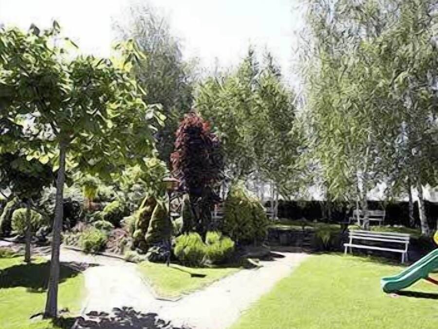 Un jardín ajardinado con un sendero, un banco y un tobogán verde.