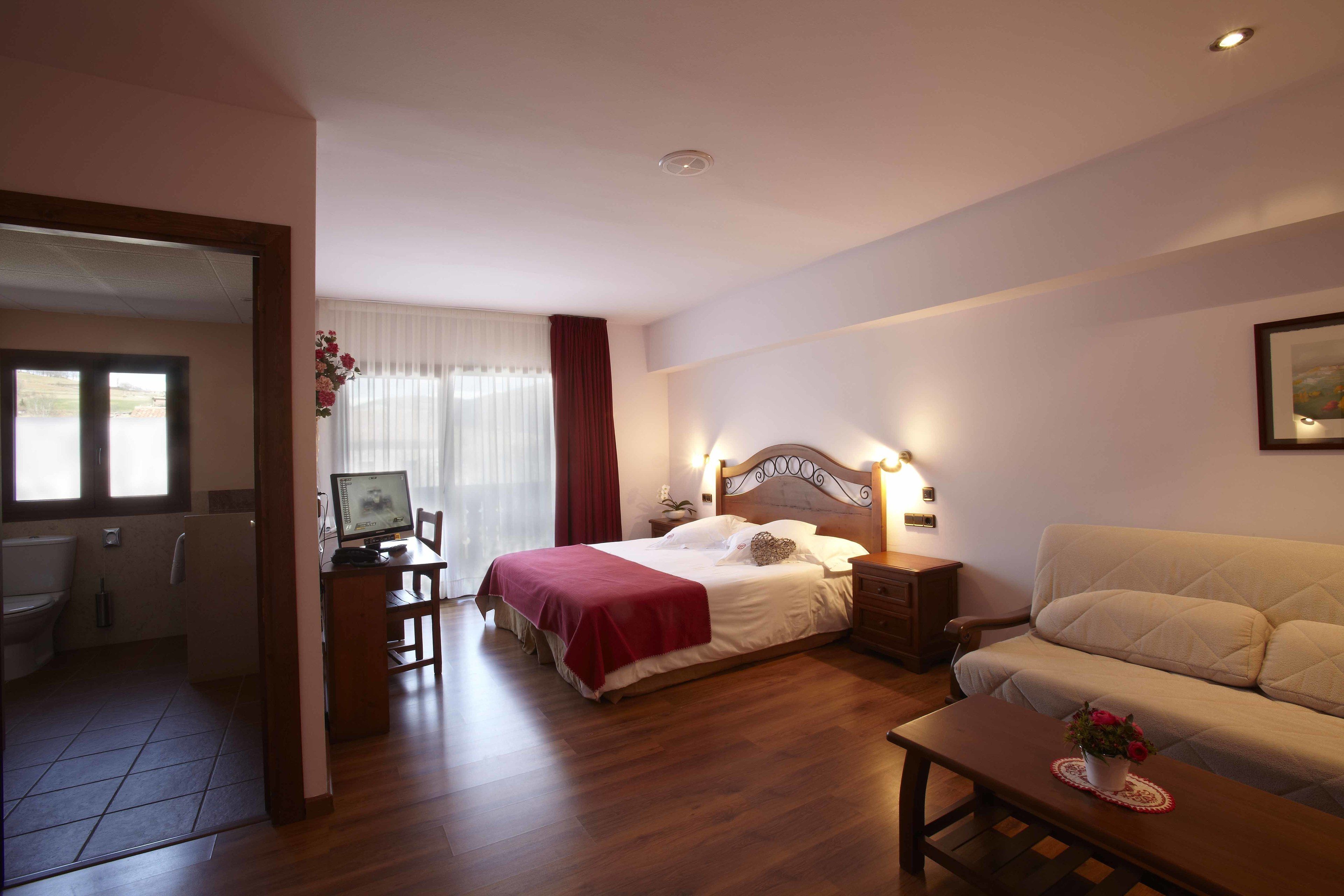 Un dormitorio con cama, mesita de noche, lámpara y un sofá.