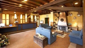 A spacious lobby with wooden beams, a reception desk, sofas, and a fireplace. - Calitxó (Mollo)