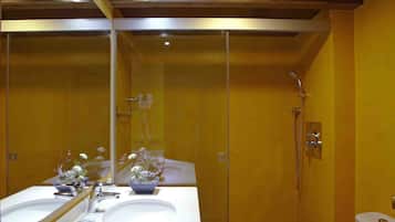 A bathroom with a white sink, mirror, and toilet. There is a shower area with a glass door and a towel rack.