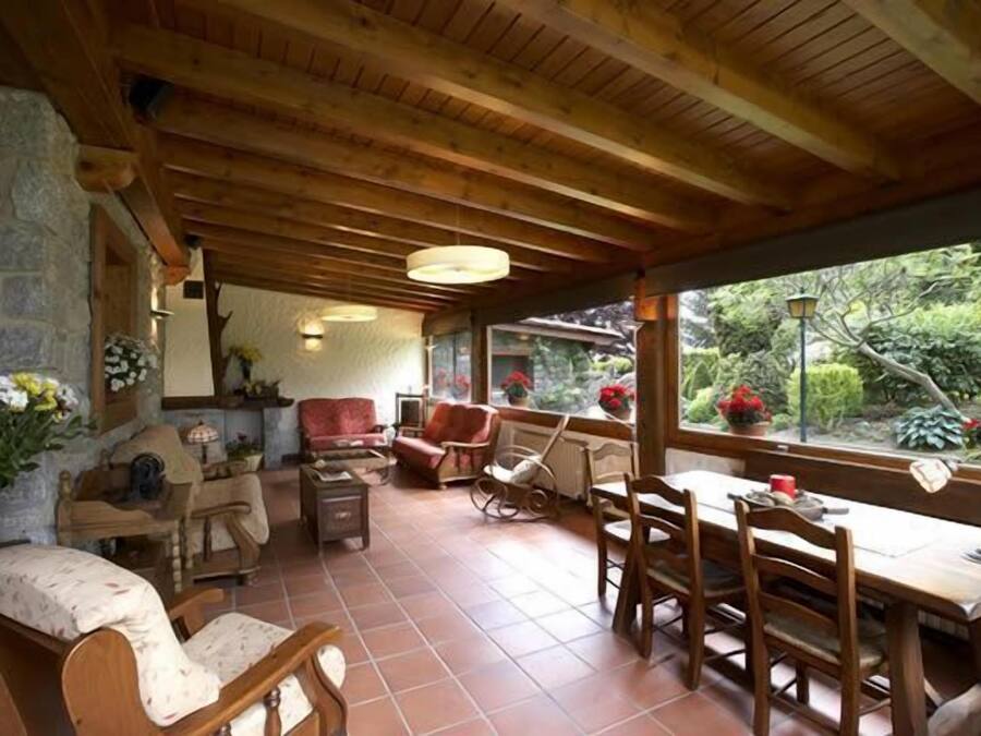 A cozy room with wooden furniture, a stone wall, and a view of greenery outside.
