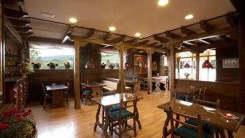 A restaurant with wooden furniture, a high ceiling, and large windows.