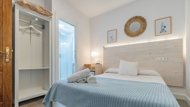 A bedroom with a bed, a wardrobe, and a door to a bathroom. - El Nogal Home - Hostel (Málaga)