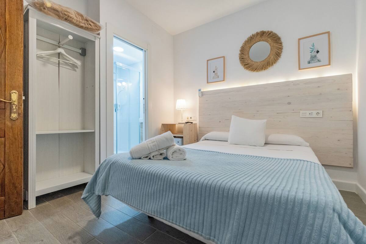 A bedroom with a bed, a wardrobe, and a door to a bathroom.