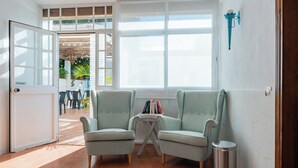 A room with two armchairs, a small table, and a trash bin. There is a door labeled "Empujar" and a window with a view of the outside. - El Nogal Home - Hostel (Málaga)