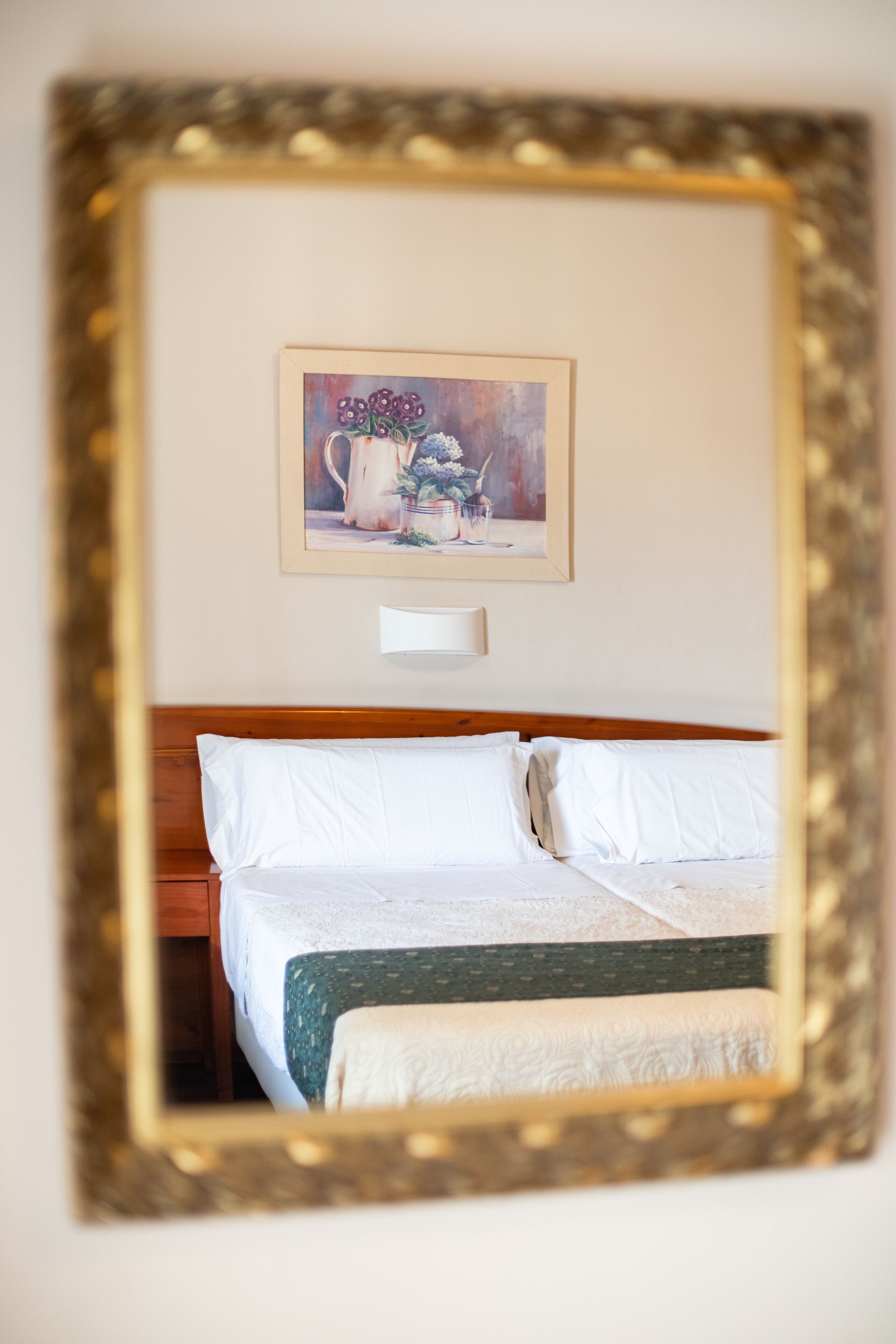 A hotel room with a bed, a nightstand, and a framed picture on the wall.