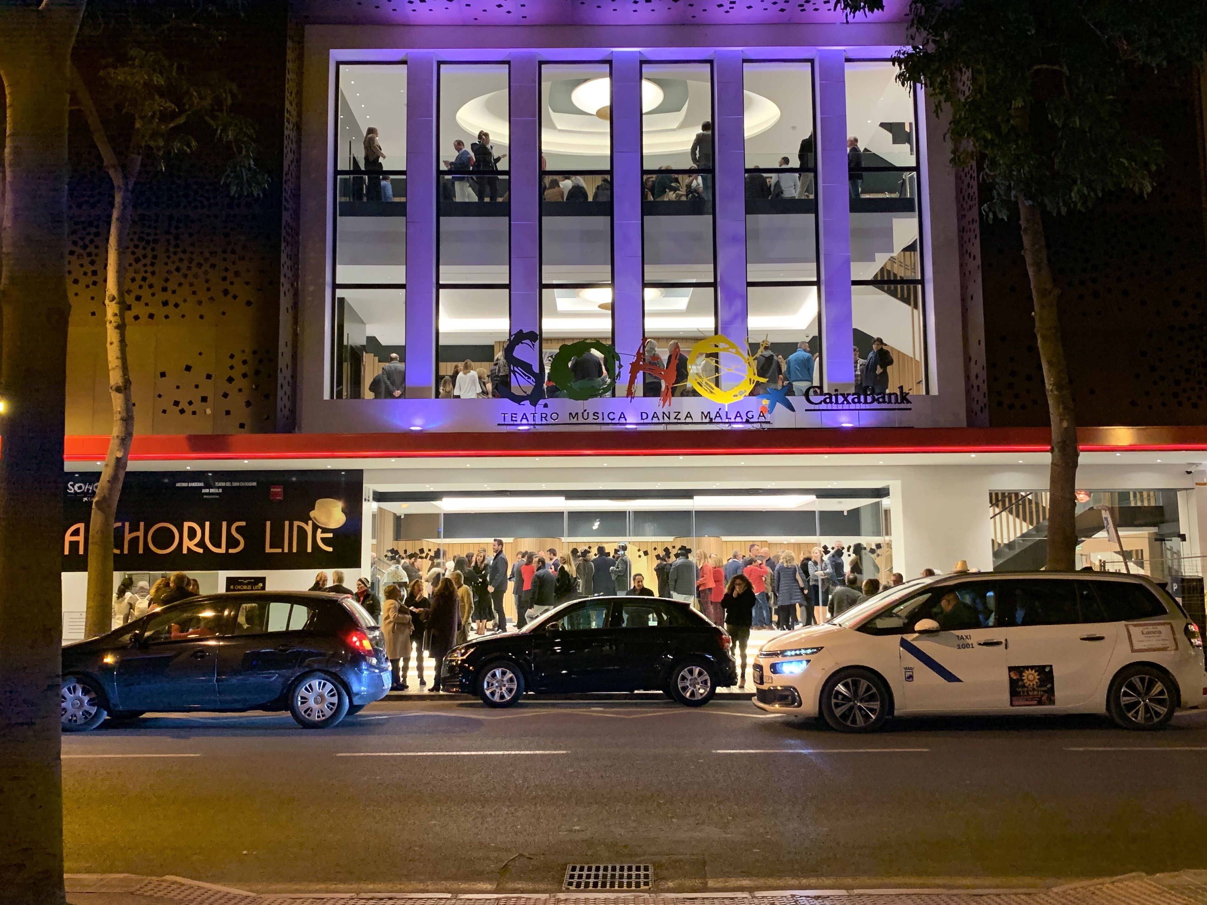 A building with a modern architectural design, featuring a large glass facade and a sign for Teatro Múgica.