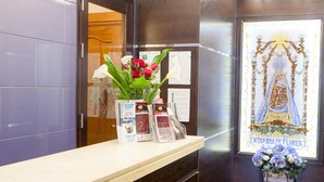 Ein Empfangsschalter mit Blumen, Informationsbroschüren und einer religiösen Statue.