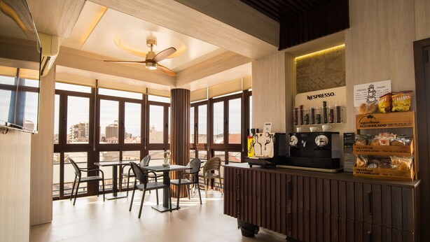 Ein modernes Café mit Barista-Station, Espressomaschinen und Blick auf die Stadt durch große Fenster.