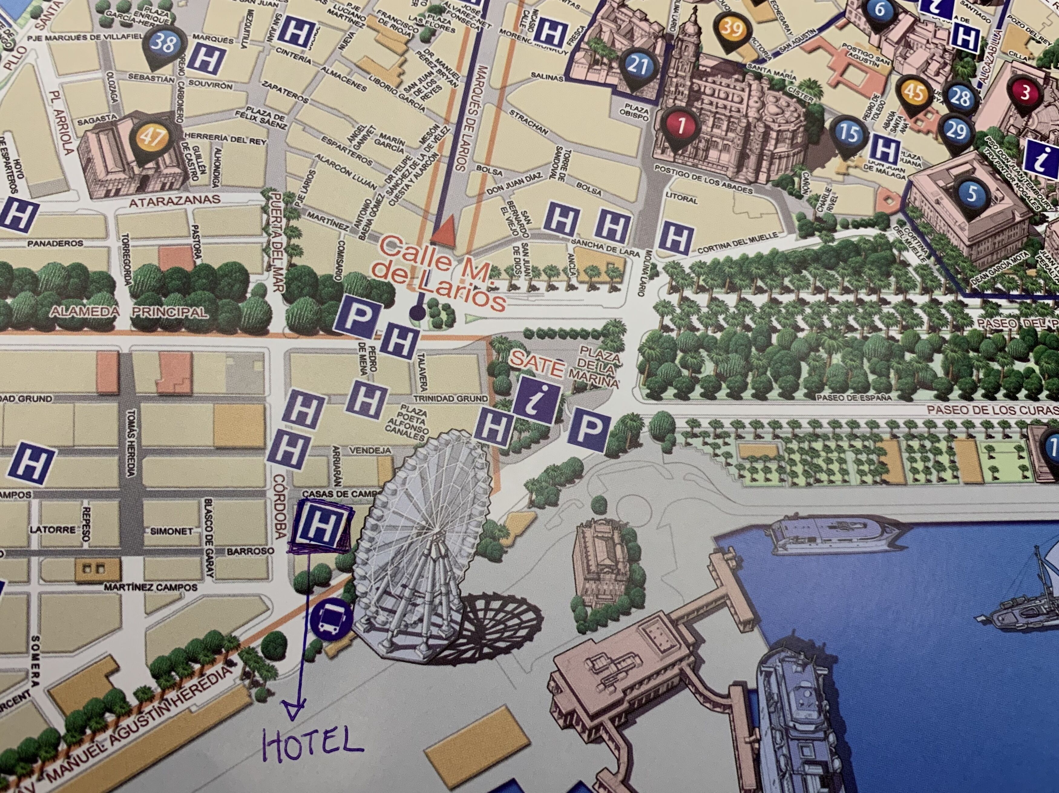 A detailed map of a city area highlighting a hotel with a Ferris wheel, a marina, and various streets and landmarks.