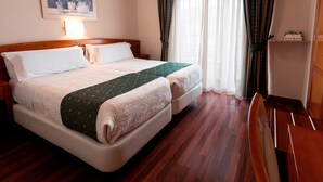Ein Hotelzimmer mit einem großen Bett, einem Holzkopfteil, einem Nachttisch, einem Schreibtisch und einem Sessel.