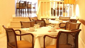 A dining area with a round table set for six, surrounded by wicker chairs. - Hotel Monclús (Palencia)