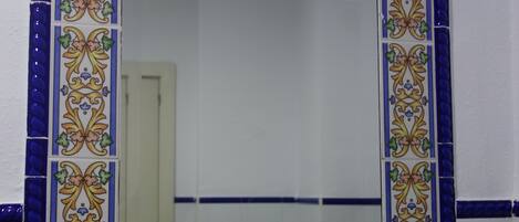A bathroom with a decorative tile border around a mirror.