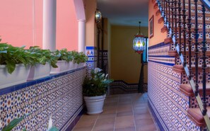 A narrow corridor with tiled walls, a potted plant, and a hanging lantern. - Hotel Doña Lina (Seville)