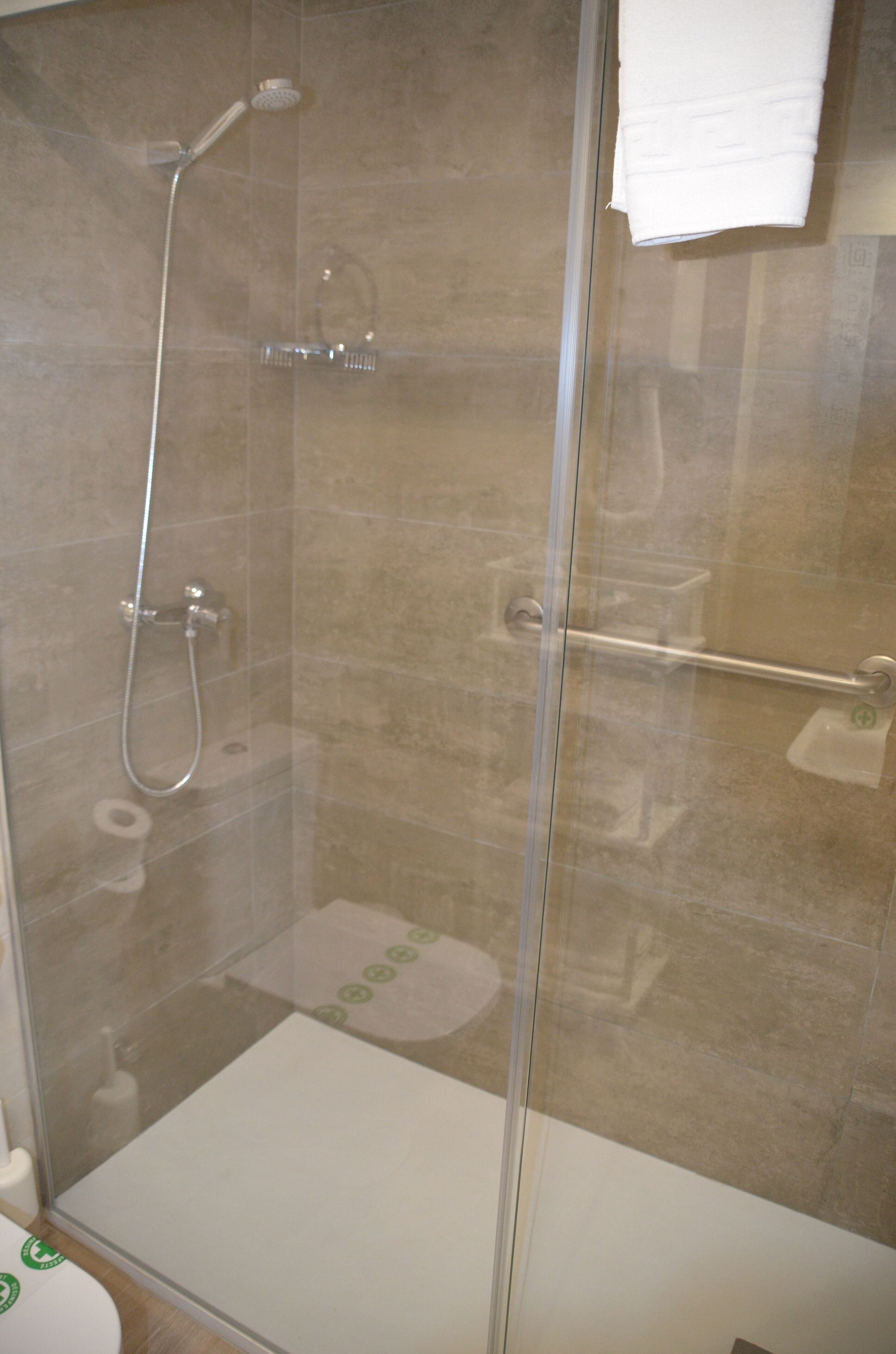 A glass-enclosed shower area with a handheld showerhead and a handheld shower head.
