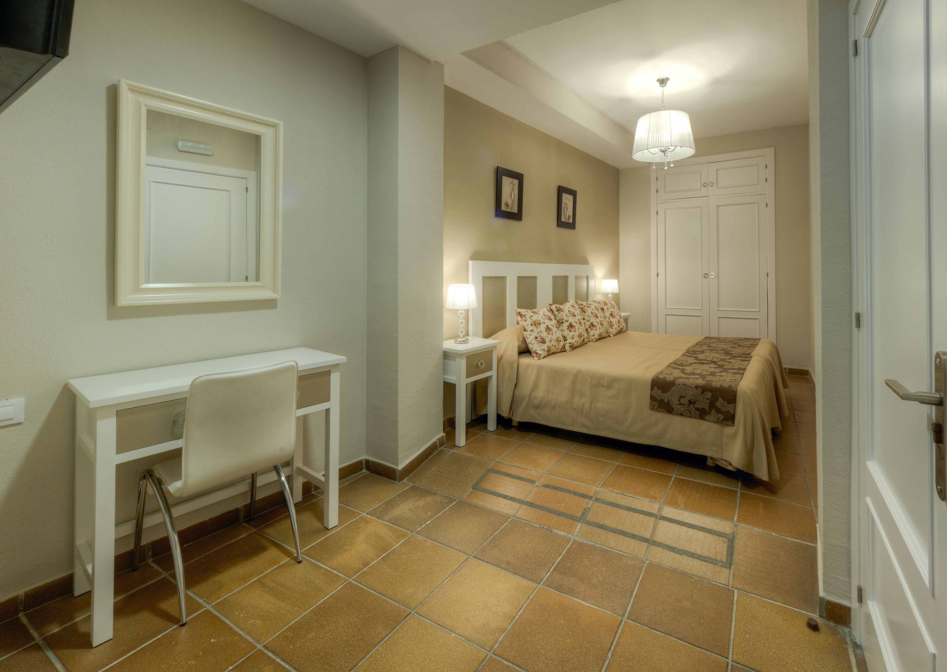 Un dormitorio con cama, mesitas de noche, escritorio y silla.