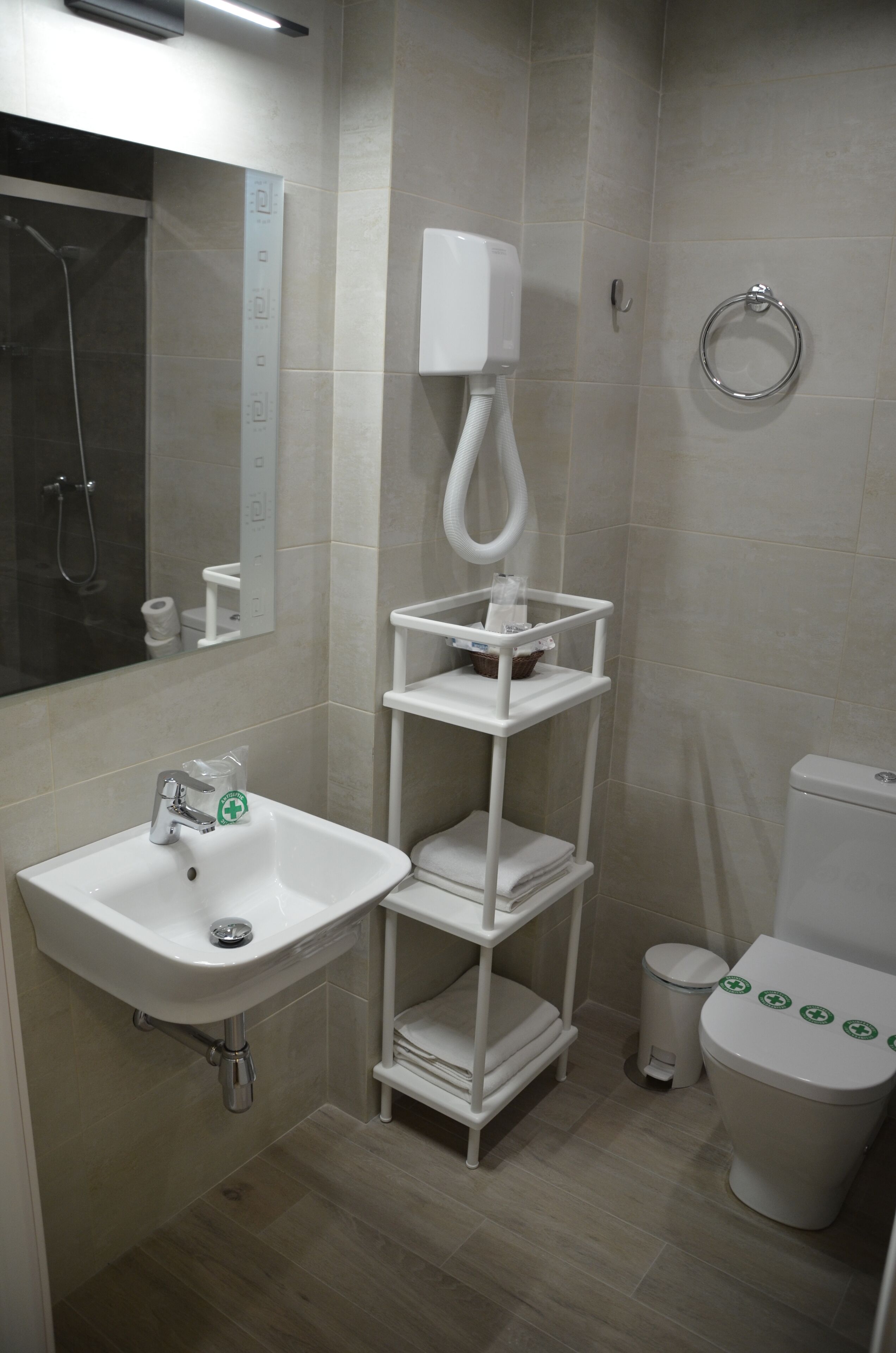 Egy modern fürőszoba, melyben fehér mosdókagyló, WC és zuhanyzó található.