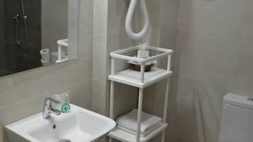 A modern bathroom with a white sink, a toilet, and a shower area.