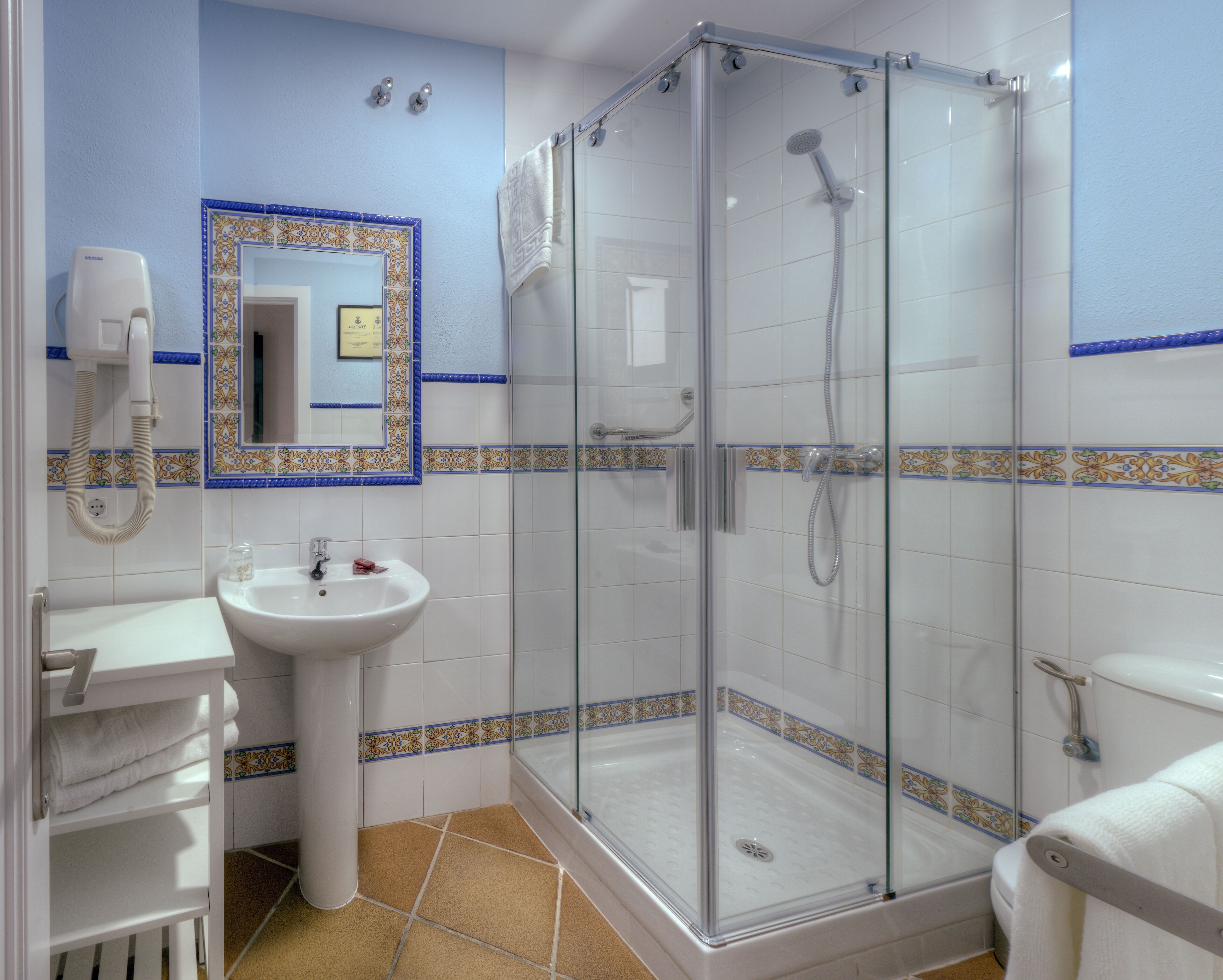 A bathroom with a glass-enclosed shower, a sink, and a toilet.