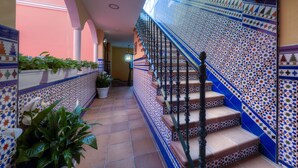 A staircase with blue and white patterned tiles, a wrought iron railing, and potted plants along the walls. - Hotel Doña Lina (Seville)