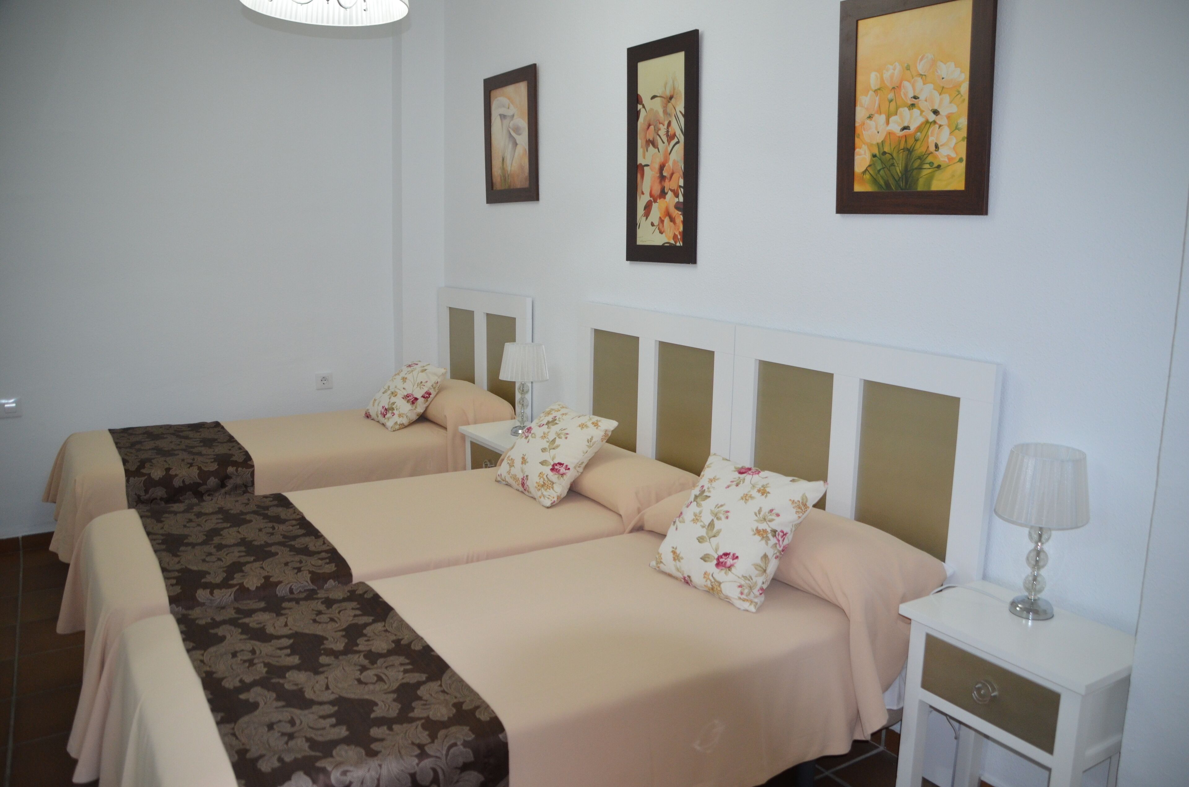 Une chambre d’hôtel avec deux lits, une table de chevet et une lampe fixée au mur.