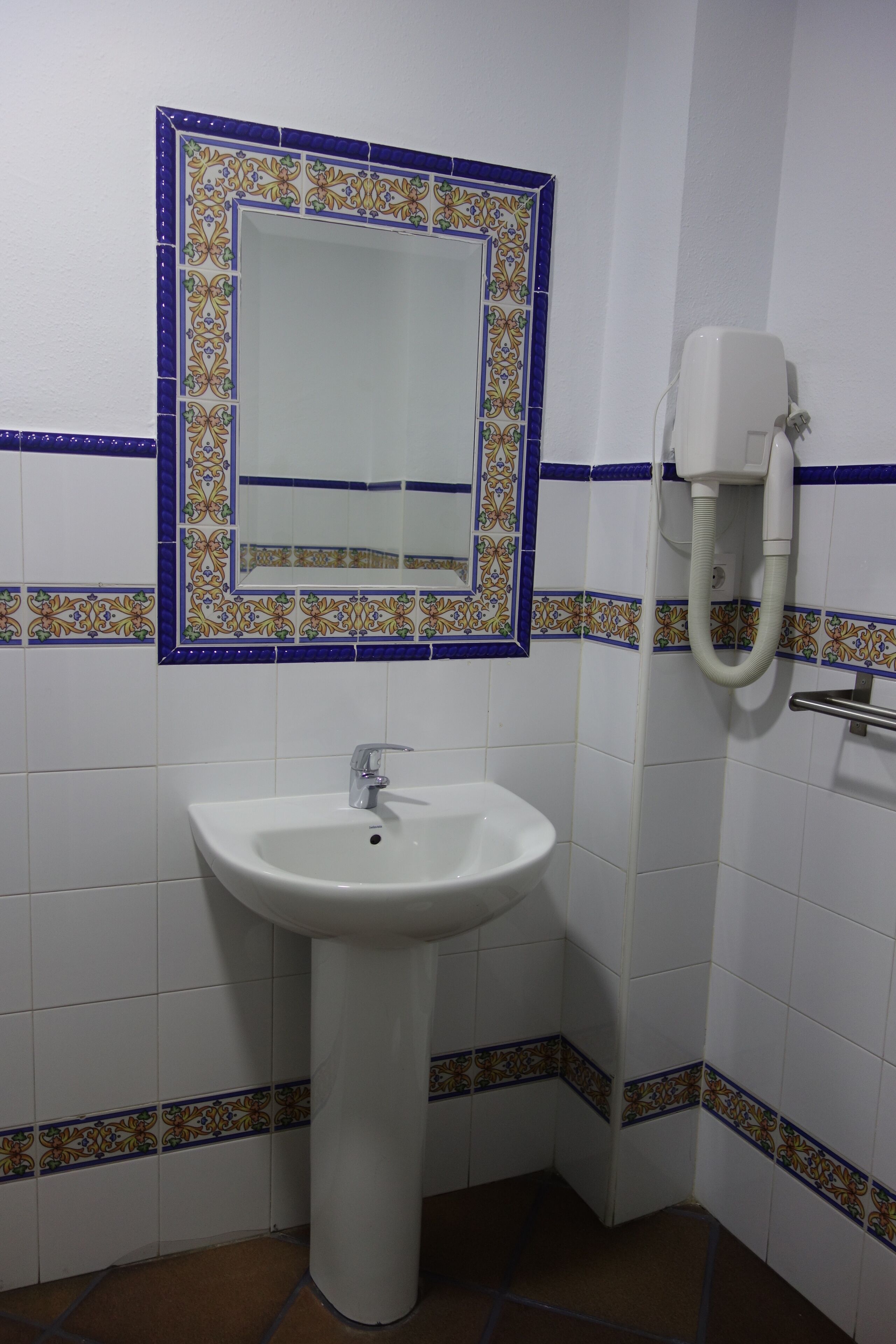 A bathroom with a white sink, a mirror, and a telephone.