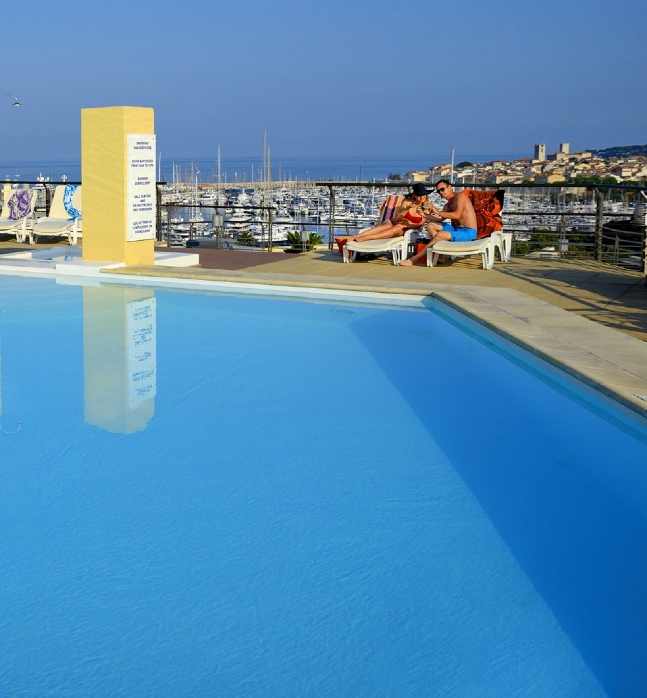 Une piscine offrant une vue dégagée sur le port de plaisance et sur le paysage urbain en arrière-plan.
