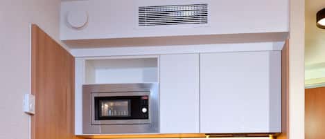 A compact kitchenette with a microwave, coffee maker, and dishwasher.