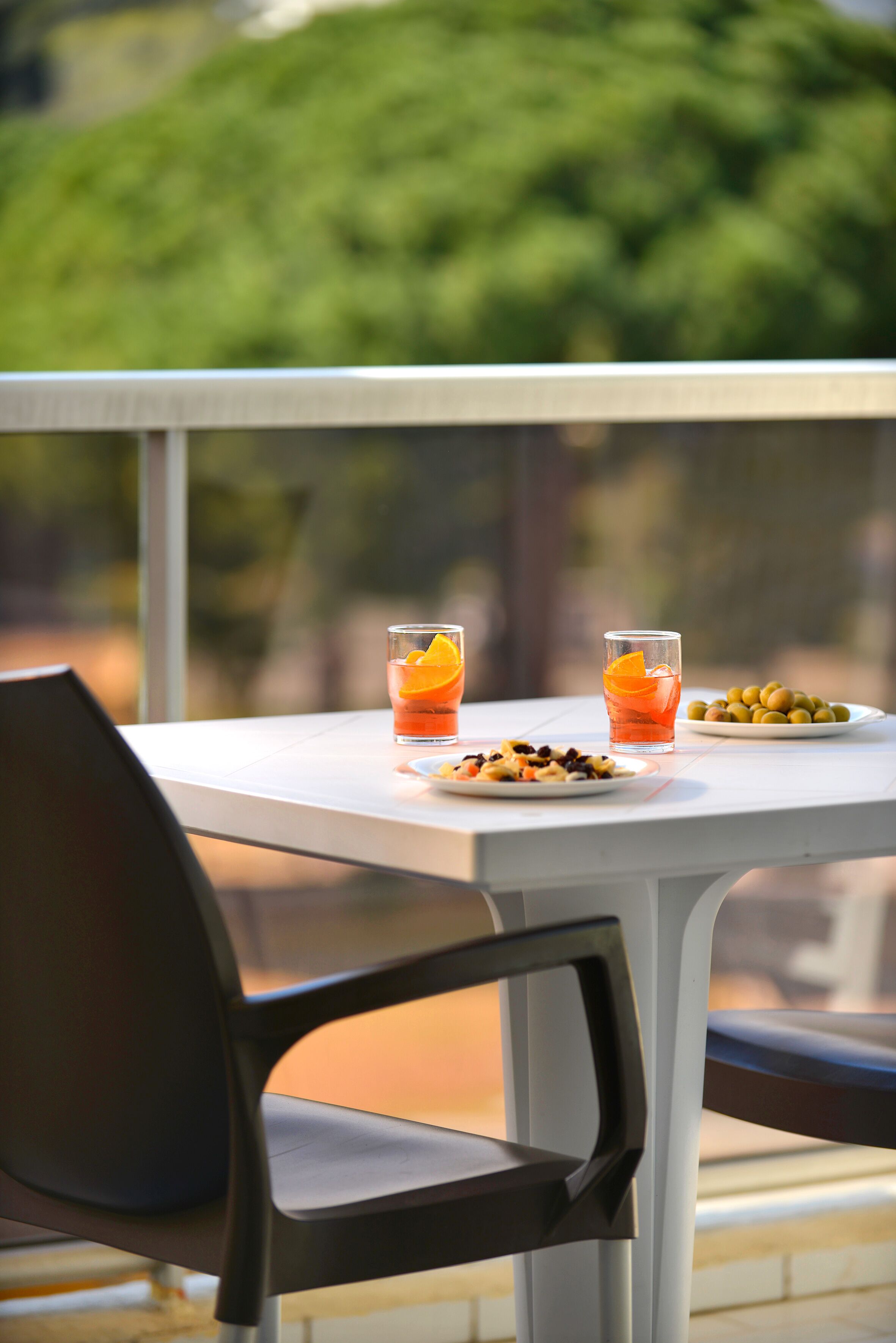 Een tafel met twee glaasjes sinaasappelsap en een bord olijven.
