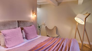 Un dormitorio con cama, almohadas, una lámpara de noche y una lámpara de pie.