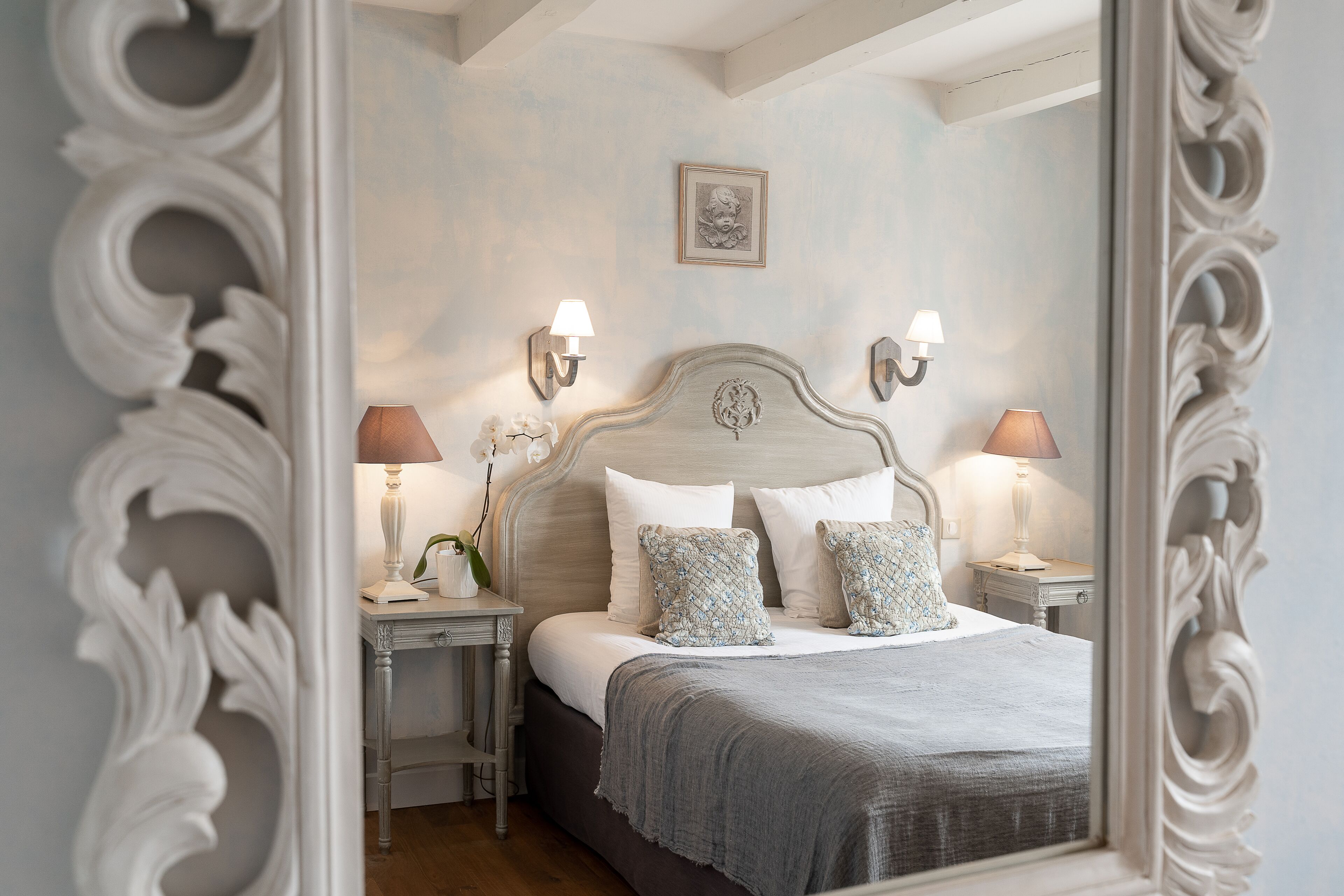 A bedroom with a large bed, two bedside tables, and a mirror.