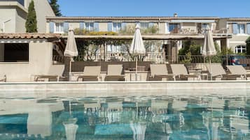 Una piscina al aire libre de temporada, sombrillas