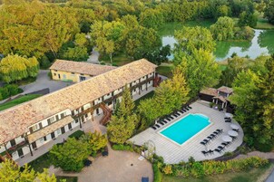 Un hotel con piscina, rodeado de exuberante vegetación y un lago.
