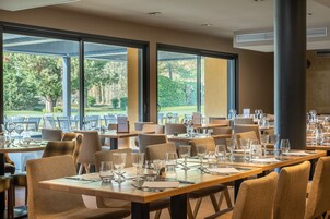 Un restaurante con mesas dispuestas para comer, amplias ventanas que ofrecen vistas al exterior y una decoración interior moderna.
