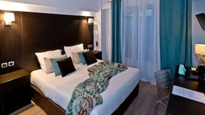 A modern hotel room with a large bed, a desk, and a chair. - ATH Hôtel Athénée (Cannes)
