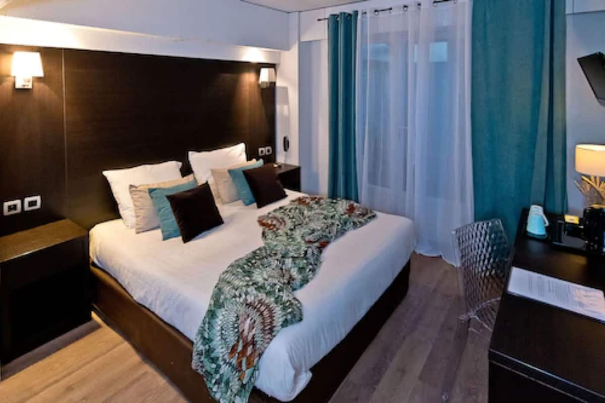 A modern hotel room with a large bed, a desk, and a chair.