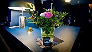 A table with a vase of flowers, a lamp, and a small photo frame. - ATH Hôtel Athénée (Cannes)