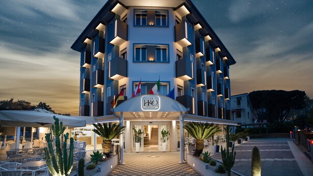Un hotel con entrada a cuadros, mesas al aire libre y cactus.