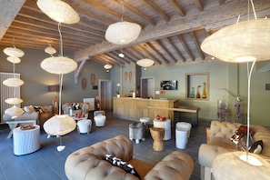 A spacious lounge area with multiple seating options, a reception desk, and a wooden ceiling. - Chalet Hôtel La Mainaz Restaurant & Resort (Mijoux)