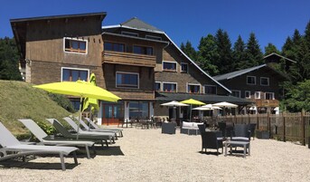 Un hotel con varios pisos, un área de estar al aire libre con sombrillas y un camino de grava.