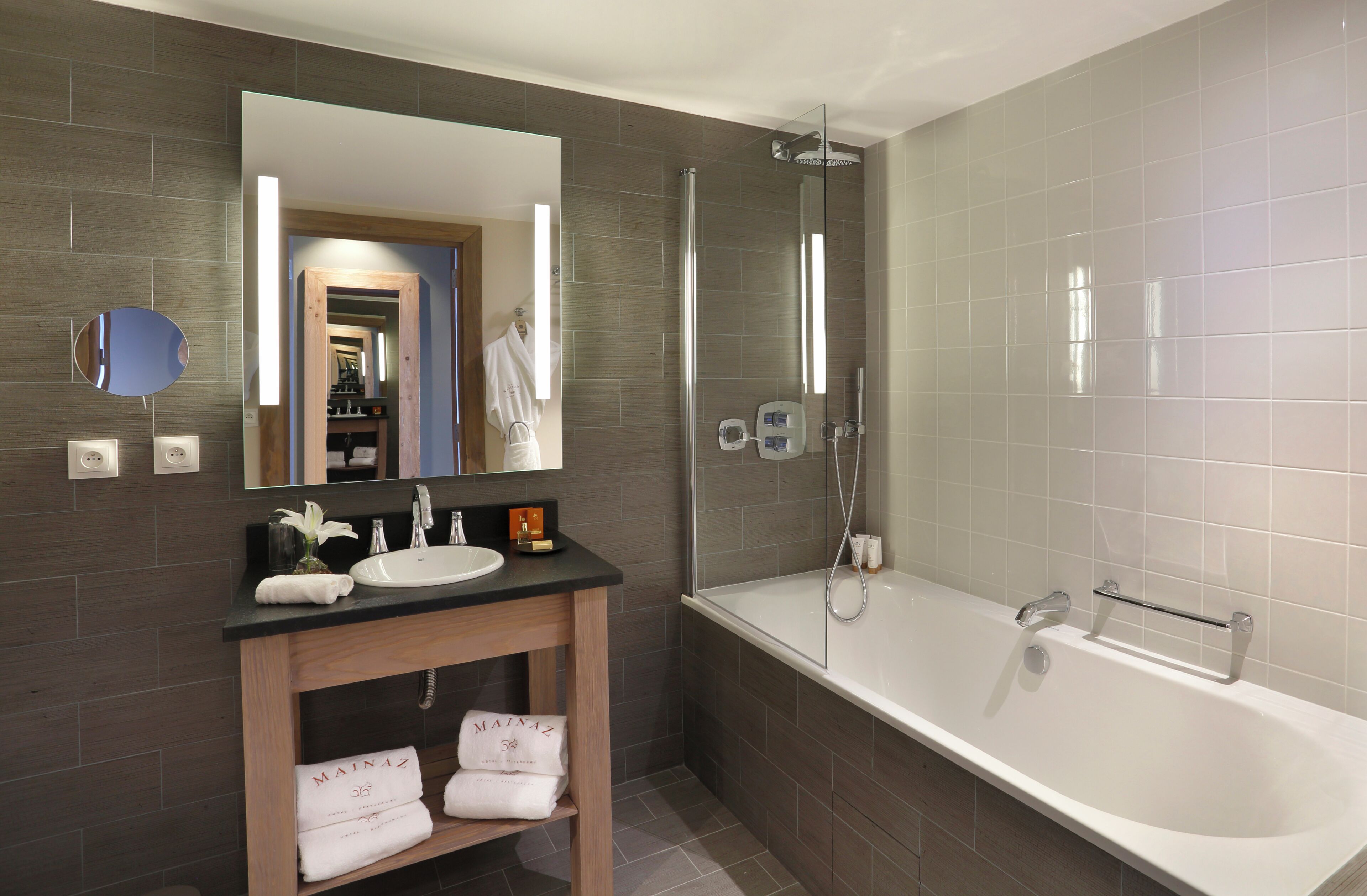 Ein modernes Badezimmer mit großem Spiegel, Waschbecken, Badewanne und Dusche.