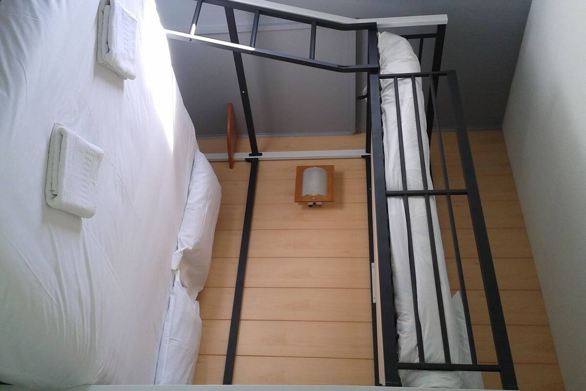 A bunk bed with a wooden floor and a small wooden ladder.