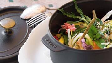 Una olla negra llena de ensalada sobre un plato blanco, con un tenedor y una cuchara en una bandeja.