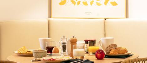 Un desayuno preparado con una mesa, sillas y un cuadro en la pared.